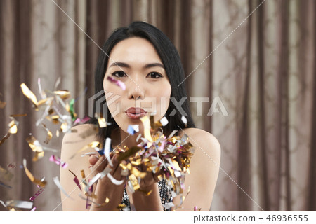 Pretty woman blowing out confetti 46936555