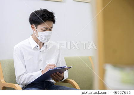 戴著面具的男性患者在醫院診所藥房的候診室寫一份調查表 46937655