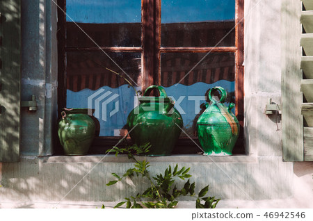 Old green ceramic pottery at old wooden window 46942546