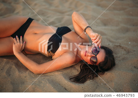 Beautiful girl sunbathing on a sandy beach. sunset silhouette 46943793