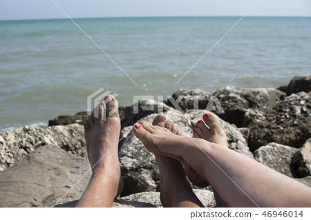 stony coast by the sea with feet of tourists 46946014
