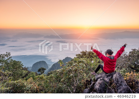 Woman sitting and raise hands up on hill with fog 46946219