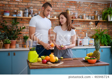 Young couple making smoothie in kitchen Young couple making smoothie in kitchen 46946724