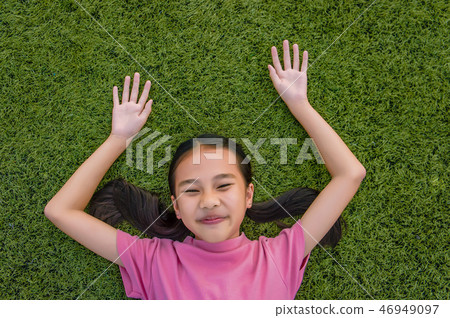 kid asian girl's lie leisurely on the Lawn floor 46949097
