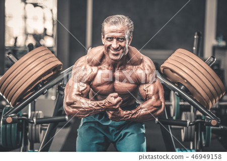 Brutal aged strong bodybuilder athletic men pumping up muscles w 46949158