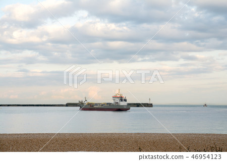 Dover's harbor A cargo ship and a lighthouse with a view into the bay surrounded by a breakwater 46954123