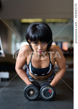 Fitness woman doing plank with dumbbells in gym Fitness woman doing plank with dumbbells in gym 46966570