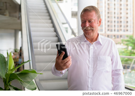 Happy senior businessman using phone in the city 46967000