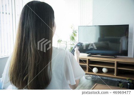 操作電視遙控的婦女 操作電視遙控的婦女 46969477