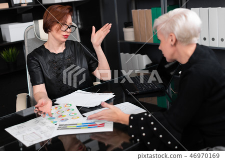 Business women discuss diagrams at Desk in office 46970169