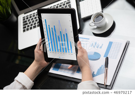 Close-up hands holding tablet on background of financial documents 46970217