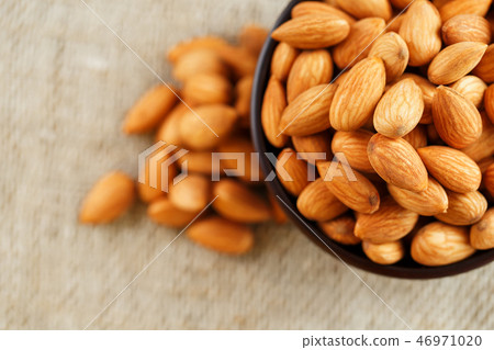 Almonds in a wooden cup on a burlap cloth . Almonds in a wooden cup on a burlap cloth . 46971020