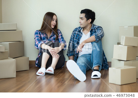 Young happy asian couple sitting on floor packing Young happy asian couple sitting on floor packing 46973048