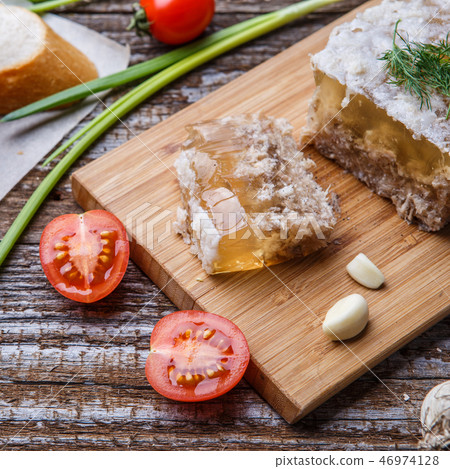 Homemade jelly meat with mustard, bread, tomatoes and garlic on the table. Holodets Homemade jelly meat with mustard, bread, tomatoes and garlic on the table. Holodets 46974128