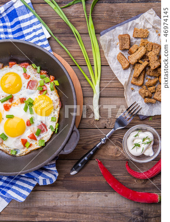 Fried eggs in pan with tomatoes and green fresh onion. 46974145