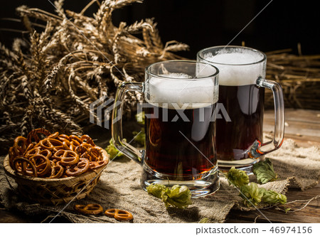 Two tankard beer with wheat and hops , basket of pretzels 46974156
