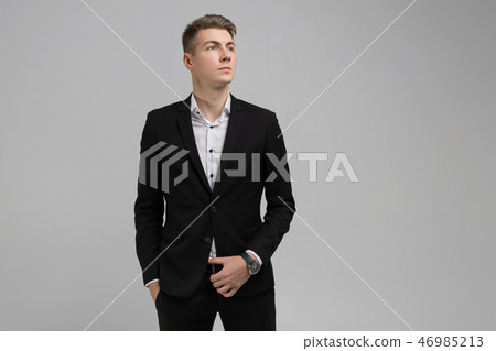 Portrait of young man with hands in pockets in black suit isolated on white background 46985213