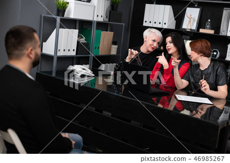 Three business women look at man in business office appraisingly 46985267