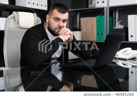 Portrait of young man sitting at table in office 46985268