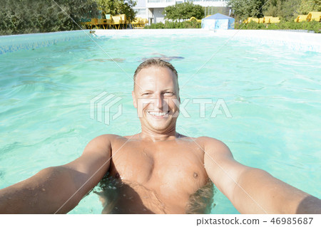 Young smiling man holding at edge of swimming pool Young smiling man holding at edge of swimming pool 46985687
