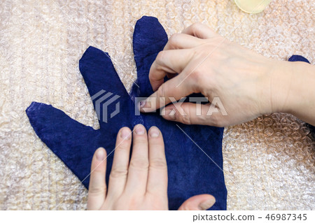 craftsman adds fibers on fingers of wet glove craftsman adds fibers on fingers of wet glove 46987345
