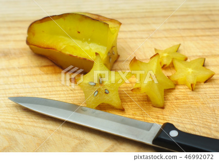 yellow sweet star fruit on cutting board with knif 46992072