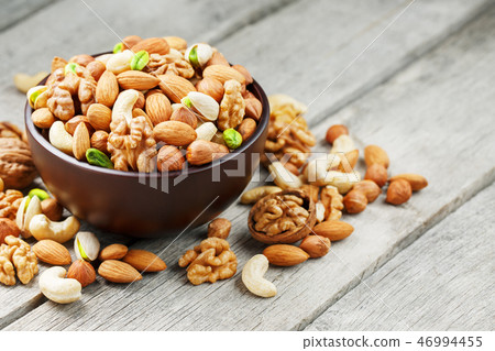 Wooden bowl with mixed nuts on a wooden gray Wooden bowl with mixed nuts on a wooden gray 46994455