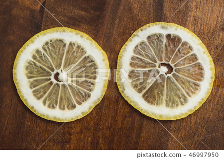 two thin slices Fresh Lemon on Wood Table Background, Rustic Style. two thin slices Fresh Lemon on Wood Table Background, Rustic Style. 46997950