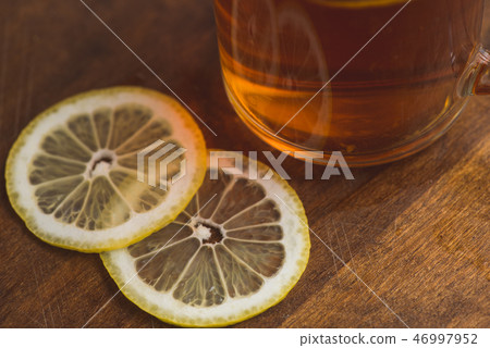 Top view of black tea with lemon in cup and on wooden plank table Top view of black tea with lemon in cup and on wooden plank table 46997952