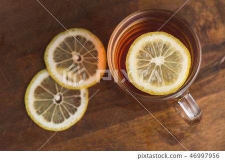 Top view of black tea with lemon in cup and on wooden plank table Top view of black tea with lemon in cup and on wooden plank table 46997956