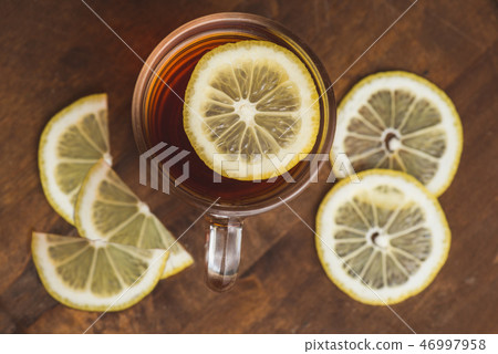 Top view of black tea with lemon in cup and on wooden plank table Top view of black tea with lemon in cup and on wooden plank table 46997958