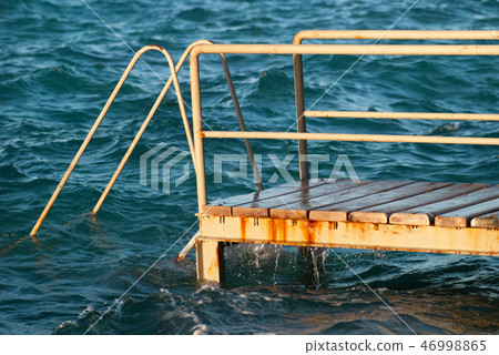 Old vintage metal wooden stairs leading to blue turquoise sea water from beach. Beautiful summer day 46998865