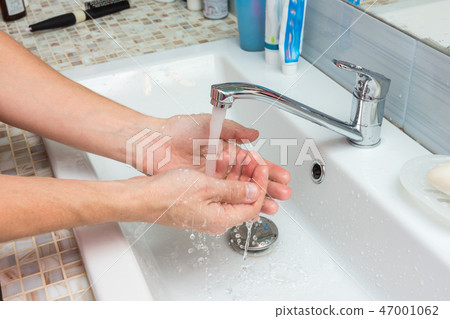 A man washes the wound under the tap 47001062