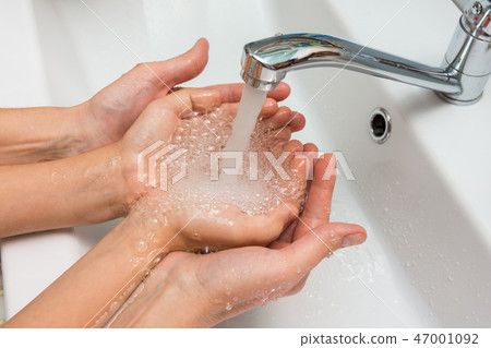 Children's and adult hands take water flowing from the mixer in the palm Children's and adult hands take water flowing from the mixer in the palm 47001092