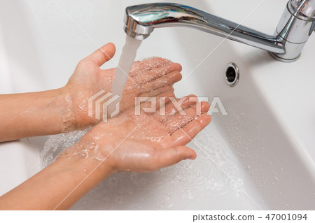 Children's hands under a strong stream of water from the mixer in the bathroom Children's hands under a strong stream of water from the mixer in the bathroom 47001094