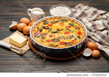 Baked homemade quiche pie in ceramic baking form, eggs and cream 47002650