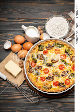 Baked homemade quiche pie in ceramic baking form, eggs and cream 47002658