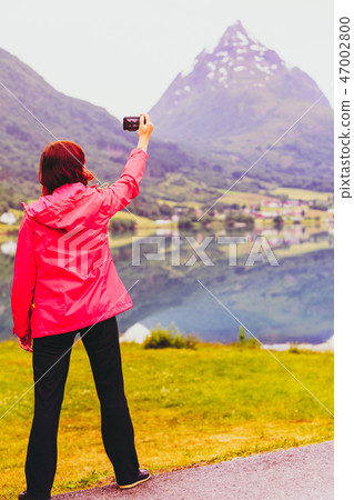 Tourist taking photo at norwegian fjord lake Tourist taking photo at norwegian fjord lake 47002800