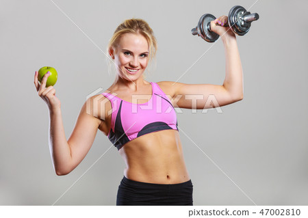 Diet fit body. Girl holds dumbbells and apple fruit Diet fit body. Girl holds dumbbells and apple fruit 47002810