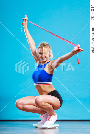 Joyful girl standing on bathroom scales 47002814