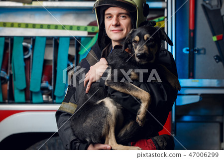 Image of young fireman in helmet with dog on background of fire truck 47006299