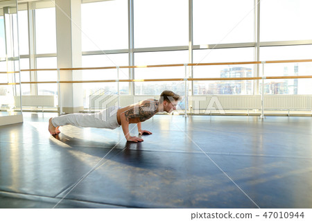 Interpreter in sportswear doing press exercises in sport hall Interpreter in sportswear doing press exercises in sport hall 47010944