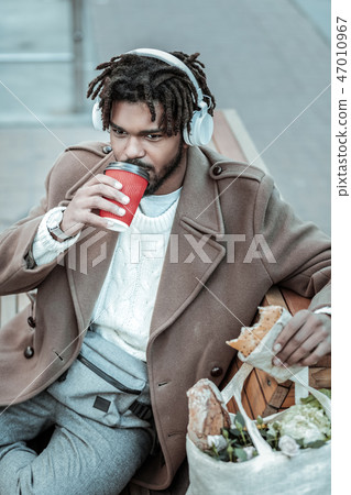 Relaxed young international man drinking hot coffee Relaxed young international man drinking hot coffee 47010967