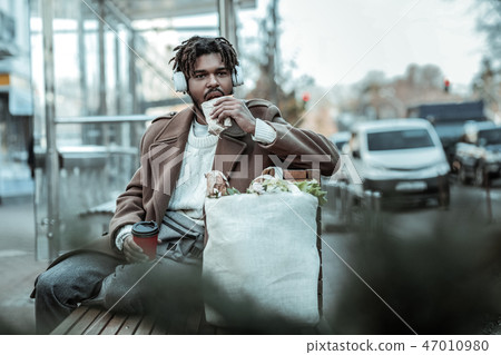 Hungry brunette man eating pastry near station Hungry brunette man eating pastry near station 47010980