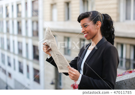 Afro American girl reading newspaper with close up of face. Afro American girl reading newspaper with close up of face. 47011785