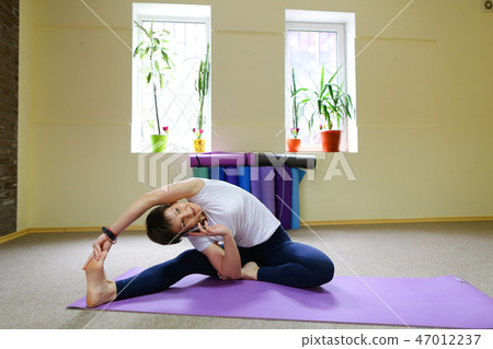Young beautiful woman sitting on floor on mat for fitness and pe Young beautiful woman sitting on floor on mat for fitness and pe 47012237
