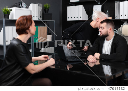 Business woman whispers something to man in ear with another young girl Business woman whispers something to man in ear with another young girl 47015182
