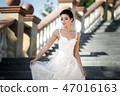 fashion photo of beautiful woman with dark hair in luxurious wedding dress posing outdoor. 47016163