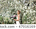 Portrait of young woman in the flowered garden in the spring time. 47016169