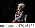 Pretty girl stands on the black background of a chalkboard and smile 47016177